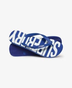 Superdry Klapki Core Logo z gumy, lekkie i wygodne – Regal Blue/Optic. Niebieskie klapki Superdry, bez wzorów, z gumy, bez obcasa. Za 113,40 zł.
