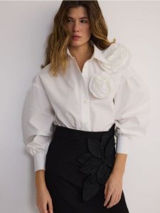 Koszula z ozdobnym kwiatem - biały. Białe koszule Reserved, l, bez wzorów, z bawełny, bez kołnierzyka, bez ramiączek. W wyprzedaży za 119,99 zł.