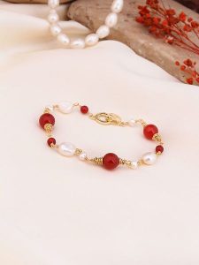Pierres de Jade Pozłacana bransoletka z perłami i koralami rozmiar: onesize. Białe bransoletki Pierres de Jade, z koralem, pozłacane. Za 43,99 zł.
