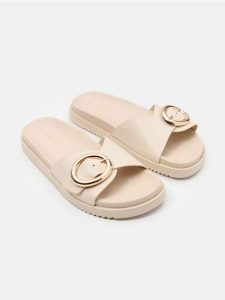 Klapki z szerokim paskiem i ozdobną klamrą z imitacji skóry - kremowy. Białe klapki Sinsay, bez wzorów, ze skóry, bez obcasa. Za 49,99 zł.
