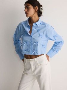 Krótka koszula z kokardkami - niebieski. Niebieskie koszule Reserved, l, bez wzorów, z bawełny, bez kołnierzyka, bez ramiączek. W wyprzedaży za 65,99 zł.