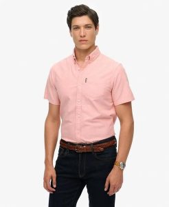 Superdry Koszula Oxford krótki rękaw Rose Pink Chambray z bawełny organicznej. Czerwone koszule Superdry, l, bez wzorów, z bawełny, bez kołnierzyka, bez ramiączek. Za 335,65 zł.
