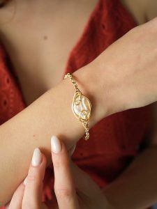 Pierres de Jade Pozłacana bransoletka z elementem ozdobnym rozmiar: onesize. Białe bransoletki Pierres de Jade, z perłą, pozłacane. Za 43,99 zł.