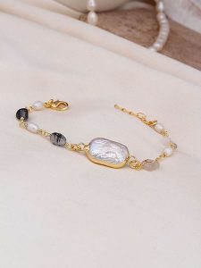 Pierres de Jade Pozłacana bransoletka z elementami ozdobnymi rozmiar: onesize. Białe bransoletki Pierres de Jade, z perłą, pozłacane. Za 43,99 zł.