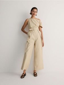 Kombinezon z paskiem - beżowy. Brązowe kombinezony Reserved, l, bez wzorów, z bawełny, bez kołnierzyka, bez ramiączek. W wyprzedaży za 89,99 zł.