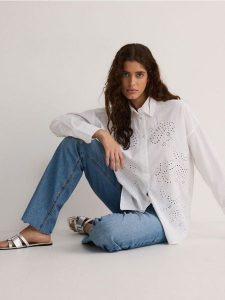 Oversizowa koszula z ażurowym haftem - biały. Białe koszule Reserved, l, w ażurowe wzory, z bawełny, bez kołnierzyka, bez ramiączek. W wyprzedaży za 59,99 zł.