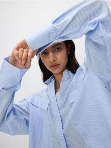 Krótka koszula z aplikacjami ze strasu - jasnoniebieski. Niebieskie koszule Reserved, l, z aplikacjami, z bawełny, bez kołnierzyka, bez ramiączek. W wyprzedaży za 89,99 zł.