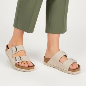 Klapki Damskie Rieker, cholewka skóra naturalna gładka dwa szerokie paski z metalowymi klamrami odkryte palce regulowane zapięcie. Szare klapki Rieker, bez wzorów, ze skóry, bez obcasa. Za 299,00 zł.