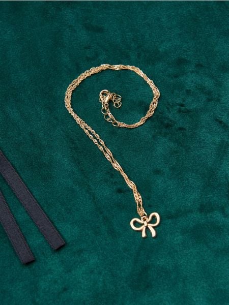 Naszyjnik z zawieszką w kształcie kokardy - złoty. Żółte naszyjniki Sinsay, złote. Za 7,99 zł.