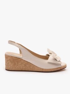 Kremowe sandały na koturnie z kokardą. Brązowe sandały Ryłko, bez wzorów, ze skóry, z okrągłym noskiem, bez obcasa, na koturnie, bez zapięcia. Za 399,99 zł.