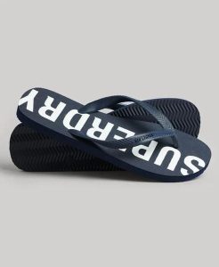 Superdry Code Core Sport Klapki gumowe – Eclipse Navy/Optic. Niebieskie klapki Superdry, bez wzorów, z gumy, bez obcasa. Za 116,60 zł.