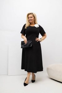 Czarna wizytowa sukienka Doris MIDI z rozkloszowanym dołem i ręcznie szytym przypinanym kwiatem w kolorze ecru PLUS SIZE XXL OVERSIZE WIOSNA. Czarne sukienki Moda Size Plus Iwanek, na imprezę, na wiosnę, plus size, z aplikacjami, z elastanu, eleganckie, bez kołnierzyka, plus size, bez ramiączek, midi, dopasowane. Za 359,90 zł.