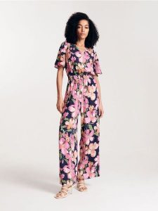 Kombinezon w kwiaty z wiskozy - granatowy. Niebieskie kombinezony Reserved, l, bez wzorów, z wiskozy, bez kołnierzyka, bez ramiączek. W wyprzedaży za 69,99 zł.