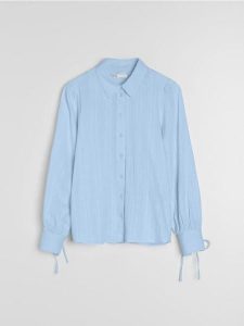 Bawełniana koszula z dekoracyjnym wiązaniem przy mankietach - błękitny. Niebieskie koszule Sinsay, l, bez wzorów, z bawełny, bez kołnierzyka, bez ramiączek. Za 49,99 zł.