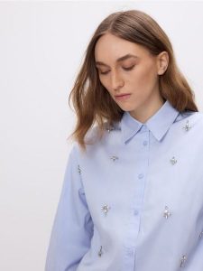 Koszula z błyszczącymi aplikacjami - jasnoniebieski. Niebieskie koszule Reserved, l, z aplikacjami, z bawełny, bez kołnierzyka, bez ramiączek. Za 149,99 zł.